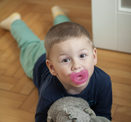 Photo d'un enfant avec sa tétine et son doudou