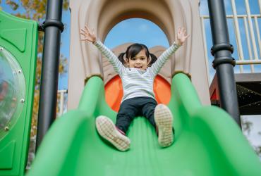 La cour s'ouvre à nous : un enfant joue dans une structure de jeu sur cour