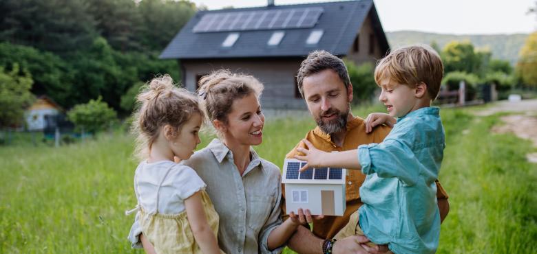 Une famille devant une maison avec des panneaux solaires